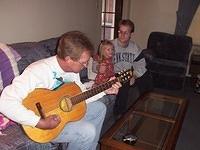 Dad playing guitar, while Carrie and Shawn listen
