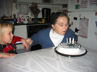 Carrie watches Mom blowing out the candles.